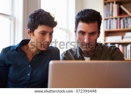 Two Businesspeople Working At Laptop In Office