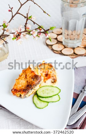 fried mackerel, fish in batter with a fresh cucumber on a light background