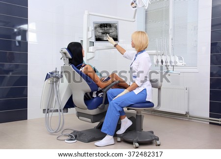 Dentist explaining x ray picture to patient on LED monitor.