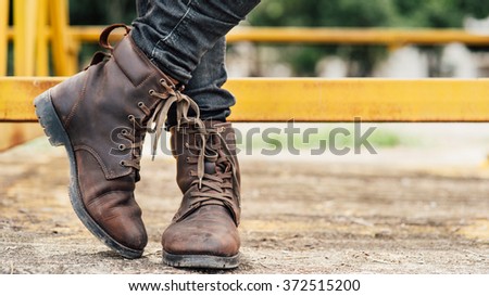 Men fashion legs in black jeans and brown leather boots