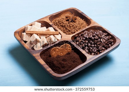Different kinds of coffee on wooden plate on blue table.