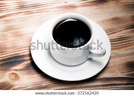 Coffee in cup on light wooden table. Toned.