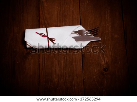 Fork in napkin on wooden background. Toned.