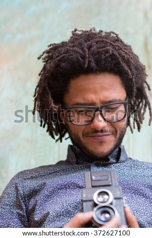 Young and creative. Handsome young Afro-American man holding camera and smiling