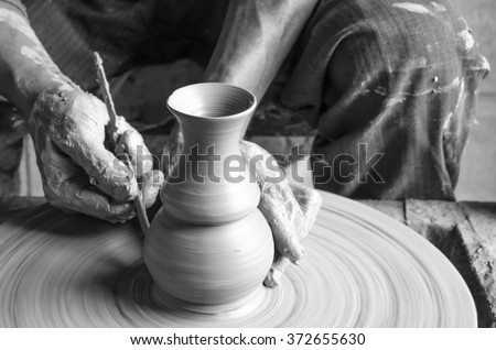 Hands of making clay pot on the pottery wheel ,grayscale,select focus, close-up.