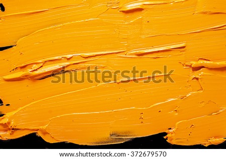 yellow-orange brush strokes of oil paint on the black  palette