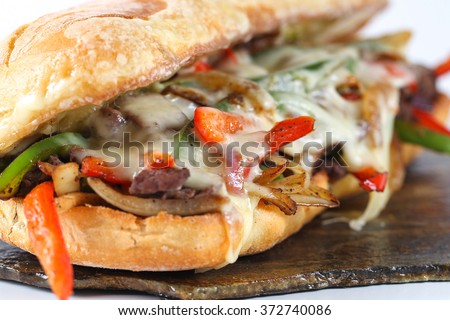 Tasty beef steak sandwich with onions, mushroom and melted provolone cheese in a ciabatta Royalty-Free Stock Photo #372740086