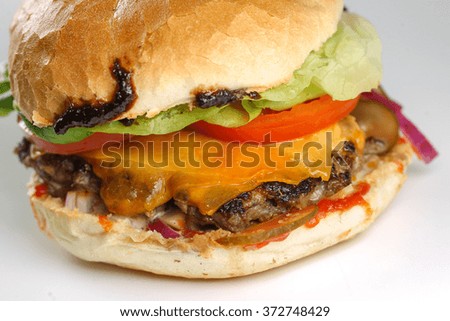 Tasty cheese beef burger with lettuce, cheddar, barbecue sauce, tomatoes, pickles and tzatziki 