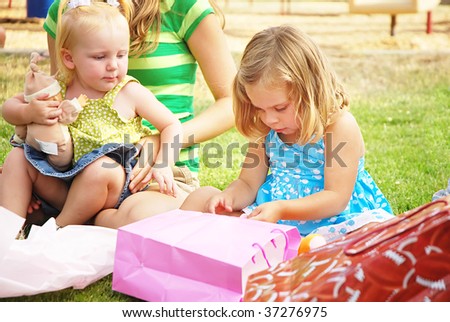 Little girl opens a present at her birthday party