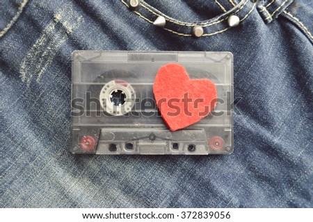 Audio cassette with magnetic tape in shape of heart on wooden background