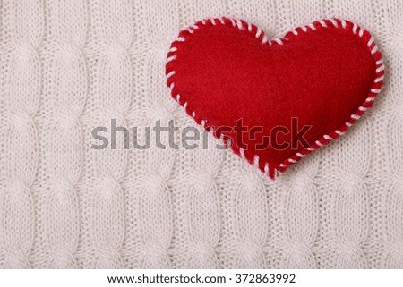 Textile red heart on a white knitted texture