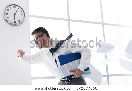 Stressed anxious businessman in a hurry checking time and running, he is late for his business appointment Royalty-Free Stock Photo #372897550