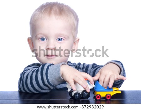 Beautiful little boy with blond hair and blue eyes holding typewriter. Child playing with small toys.