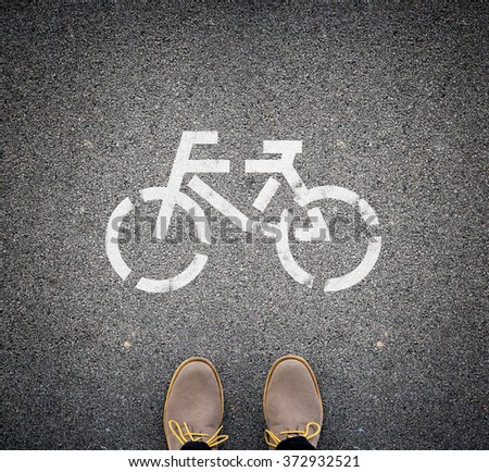 Two brown boots standing on asphalt in front of a picture of a bike. Top view. Concept of eco traveling. Royalty-Free Stock Photo #372932521