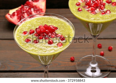 Fresh healthy kiwi drink with pomegranate on wooden background 