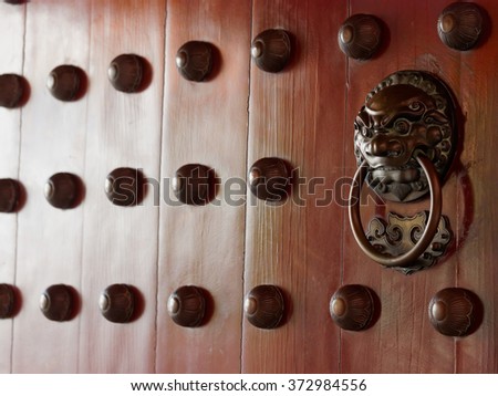 Traditional Chinese doors with brass handles symbolic of lion's heads. It's believe to ward off evil and usher in good luck for the occupants.