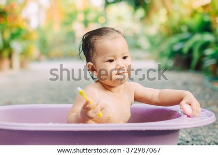A baby bathing brushing teeth in the garden : selective focus picture.