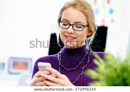 Business woman in office holding mobile phone