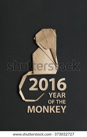Folded paper origami monkey on black background. 2016 year of the monkey lettering vertical postcard.