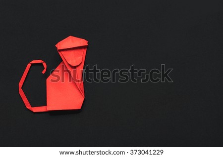 Folded red paper origami monkey on black background. Postcard template.