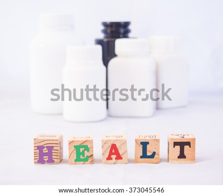 Heath care idea picture of "Health" wording on wooden cubic with medication container background