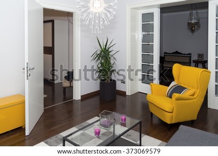 Modern Hotel Apartment with 3d Living Room and Bedroom Interior, White Walls. Luxury Livingroom with Sofa and Armchair in Corner. Room for Rent with Bed or Couch, Beautiful Curtain and Large Flat TV.
