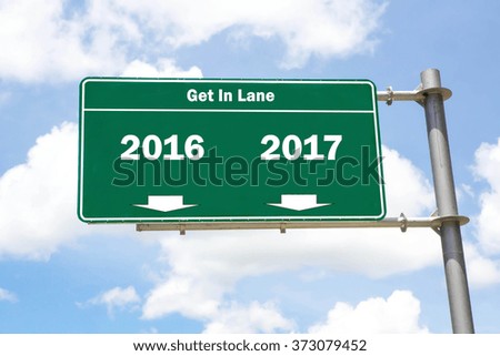 Green overhead road sign with the instruction to get in lane with a 2016 or 2017 concept against a partly cloudy sky background.