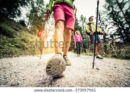 Group of hikers with backpacks and sticks walking on a mountain at sunset - Four friends making an excursion in the nature Royalty-Free Stock Photo #373097965