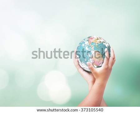 Corporate social responsibility (CSR) concept: Two human hands holding earth globe over blurred nature background. Elements of this image furnished by NASA