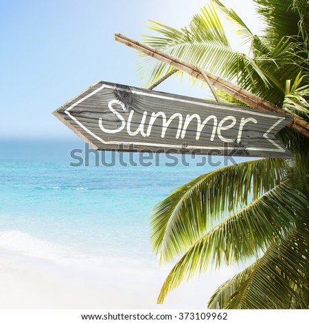 Wooden sign Summer on tropical white sand beach summer background. Lush tropical foliage and sunshine. Blue ocean at perfect day. No people.