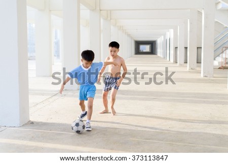 Young Asian boy play football in the empty white building.