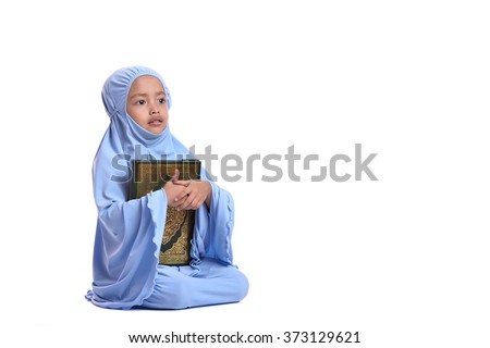 Young Asian Muslim girl in blue hijab hold Al Quran