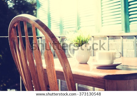 White coffee cup and vase plant on table at patio with outdoor view - Vintage Filter