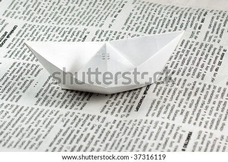 Paper ship over a newspaper
