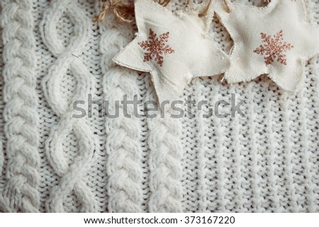 Closeup image of handmade knitted pattern and couple of decorative stars