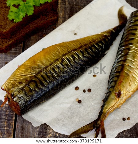 Whole smoked fish (mackerel) on a dark wooden table