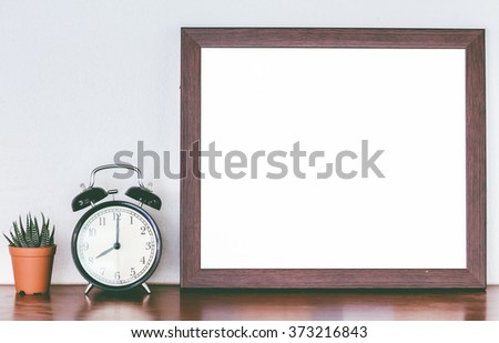 Wooden frames and alarm clock with cactus on table
