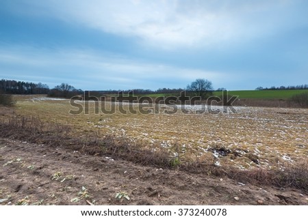 Winter or early spring landscape of fields under cloudy sky. Sad landscape