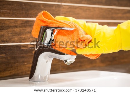 Woman doing chores in bathroom, cleaning modern tap.