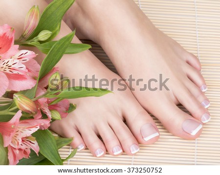 Closeup photo of a female feet with white french pedicure on nails. at spa salon. Legs care concept