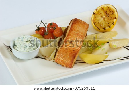 Close-up Plate of fried fish, potatoes, lemon, tomato, green onion, garlic sauce