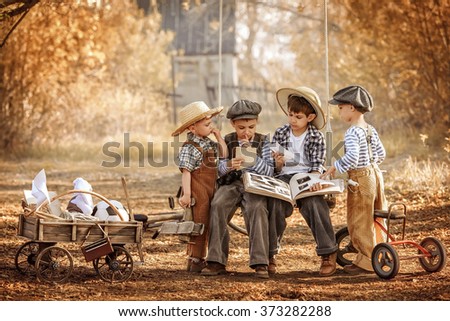 Children watch a photo album sitting on a swing in the shade of the trees a summer day