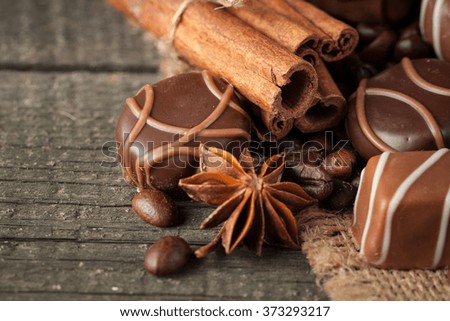 Assortment of dark, white and milk chocolate stack, chips. Chocolate and coffee beans on rustic wooden sacking background. Spices, cinnamon. Selective macro focus. Chocolates background. Sweets