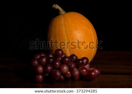 Pumpkin and grapes in the dark background, studio picture