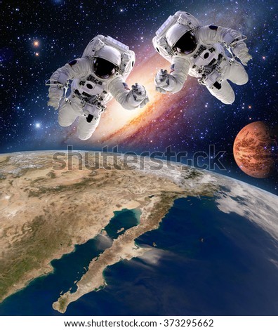 Two astronauts spaceman planet spacewalk outer space walk moon mars galaxy. Elements of this image furnished by NASA. Royalty-Free Stock Photo #373295662
