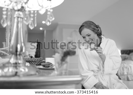 Young bride having quick snack while getting ready at hotel room. Bridal happy moments. Wedding picture in black and white. 