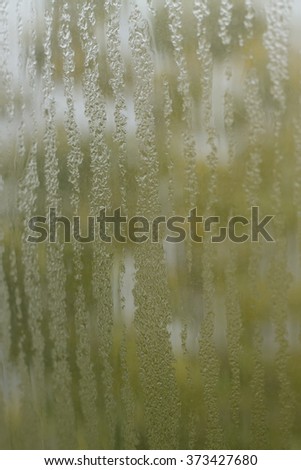 natural water drops on window glass with green background. vertical image