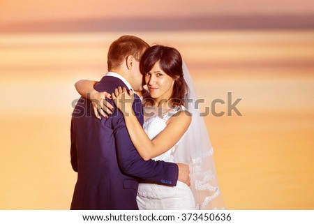 Beautiful couple is embracing at golden summer sea sunset background.