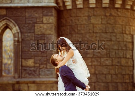 Portrait of beautiful wedding couple having fun at vintage castle with golden sunset background.