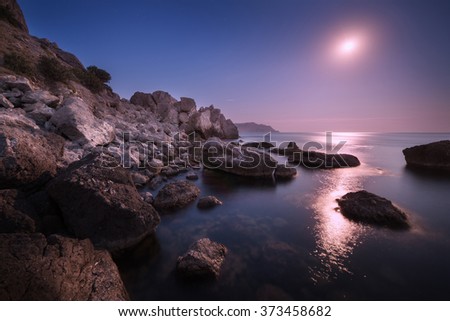 Colorful seascape with moon and lunar path with rocks at night in summer. Mountain landscape at the sea
